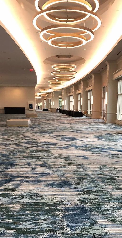 Blue and cream abstract wave pattern wall to wall carpet in hotel corridor