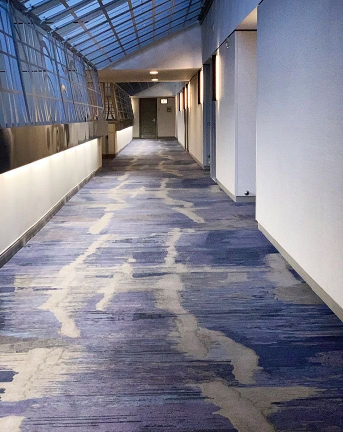 Violet and cream marbled pattern wall to wall carpet under glass skylight corridor
